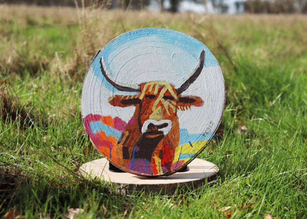 art at the farm artwork - a wooden disk with a highland cow