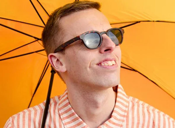 An image of Harry Baker in sunglasses with an umbrella