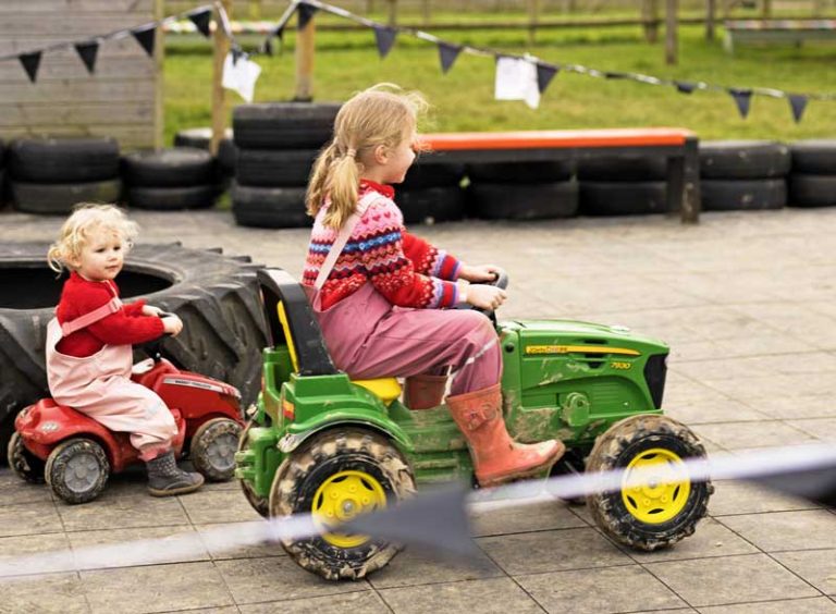 two children riding ride-on tractors