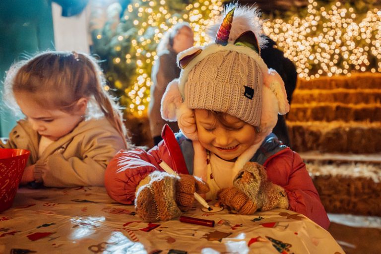 Two children doing a Christmas craft in a sparkly barn